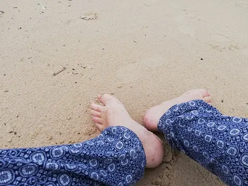 Pés sentados no areal de uma praia