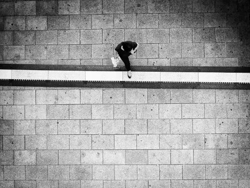 Fotografia vista de topo, de uma pessoa a cruzar um marca branca no chão